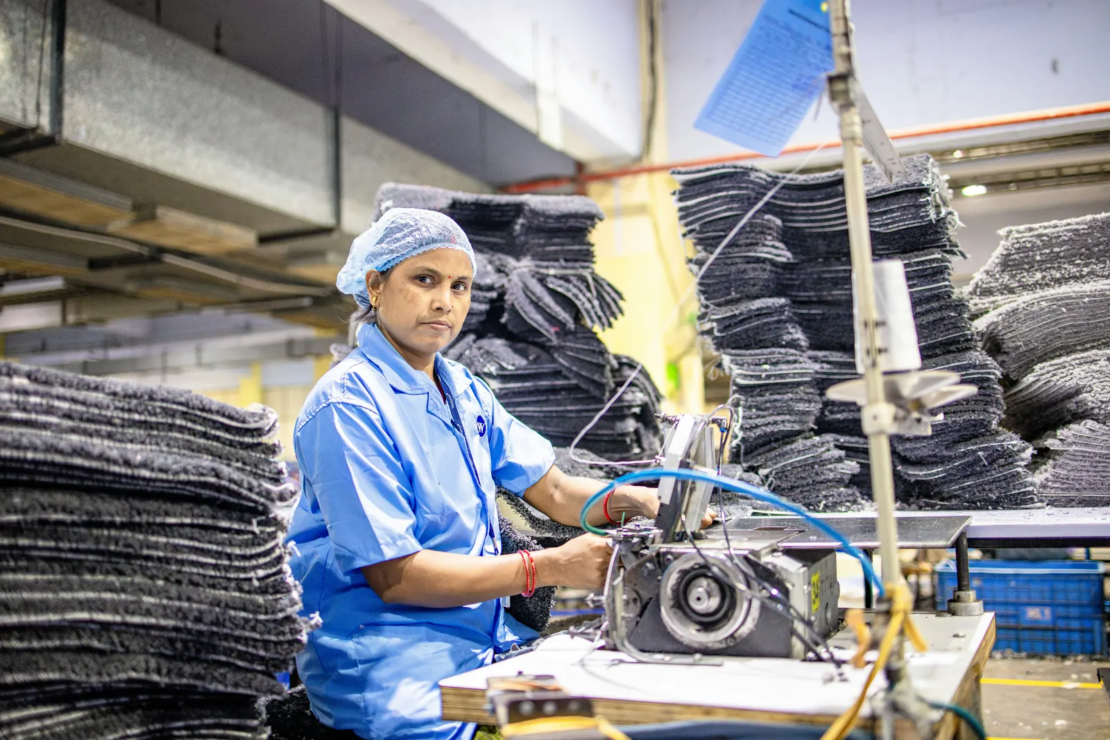 A machine operator stitching fabric on an industrial sewing machine